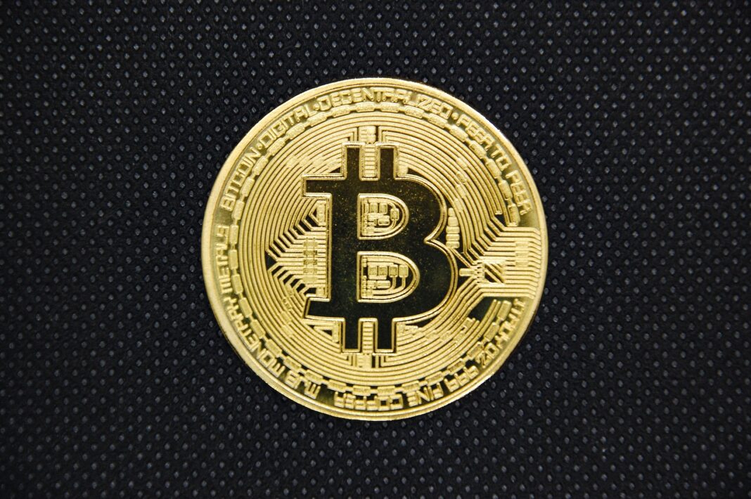 A gold physical Bitcoin coin on a dark surface, symbolising the Bank of England's Digital Sterling initiative in 2026.