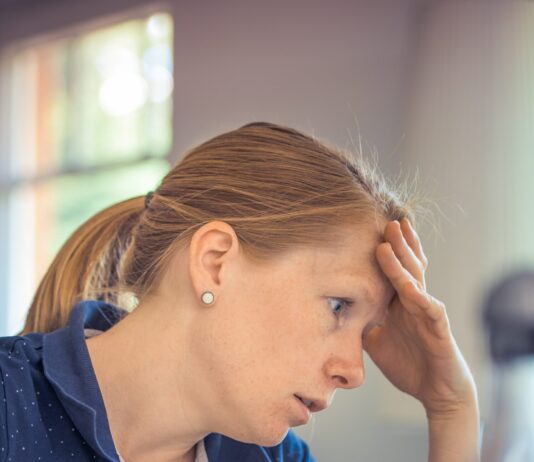Stressed female employee staring at a laptop, experiencing burnout and exhaustion from the 8-hour workday.